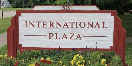 a sign for international plaza in front of a garden