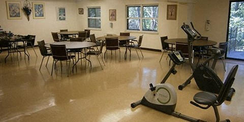 a gym room with tables and chairs and a treadmill