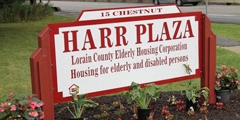 a sign for harr plaza in a garden