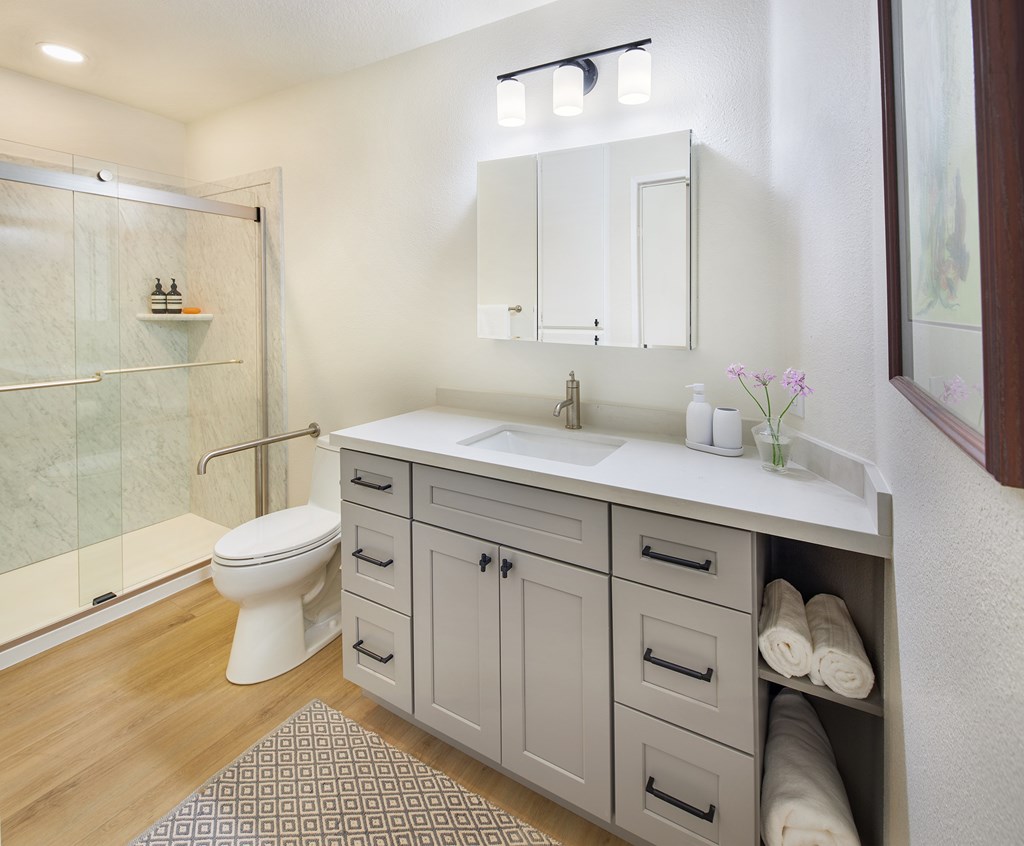 A bathroom with a white toilet, sink, and cabinets.