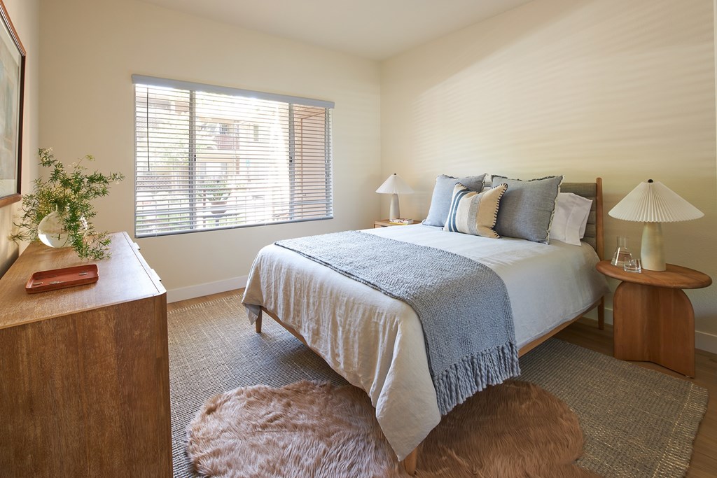 A bedroom with a bed, a nightstand, and a rug.