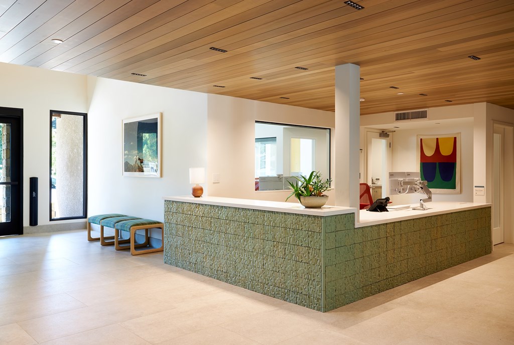 A reception area with a green reception desk and a wooden ceiling.