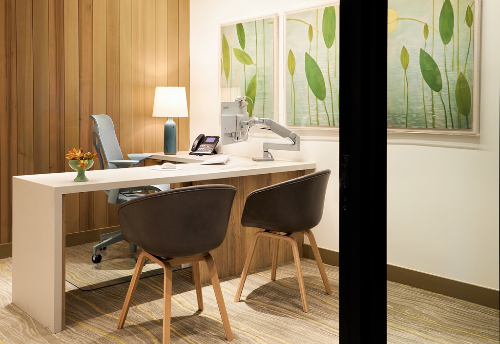 A modern office with a wooden desk and two chairs.