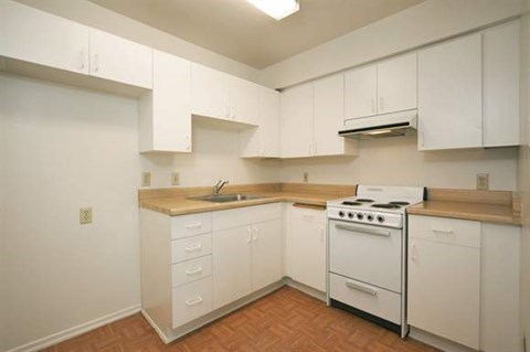 a kitchen with white cabinets and a stove and a sink