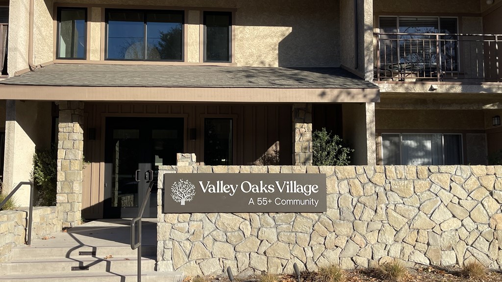 A sign that says Valley Oaks Village in front of a building.