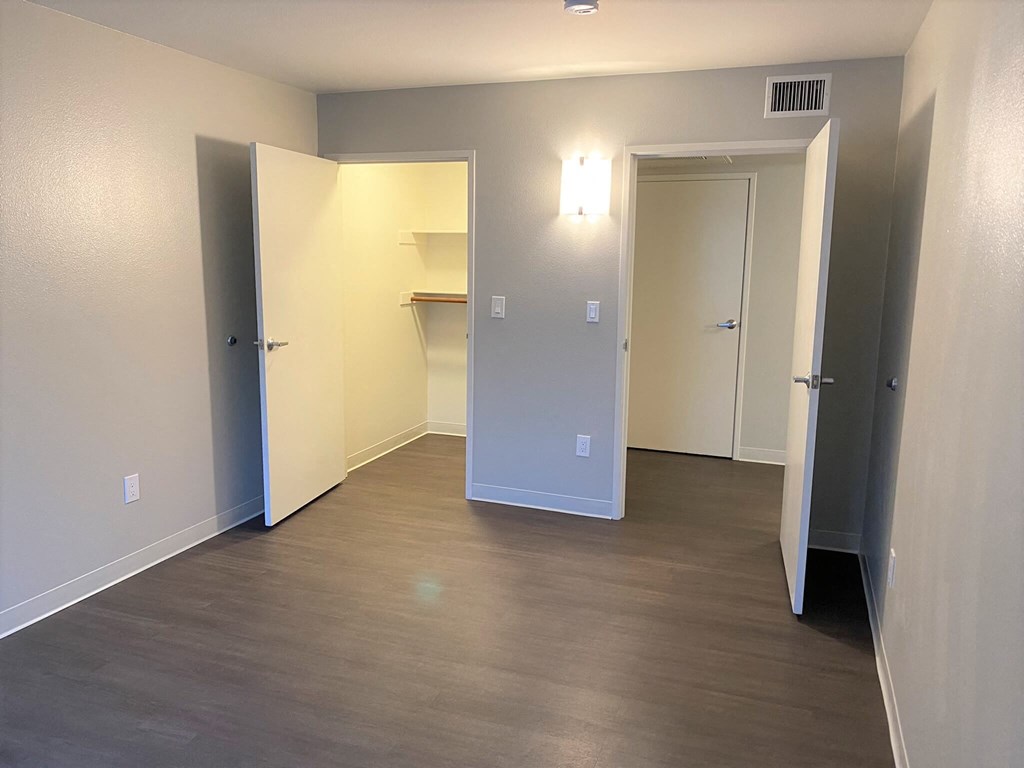 a room with a hard wood floor and a hallway with two doors