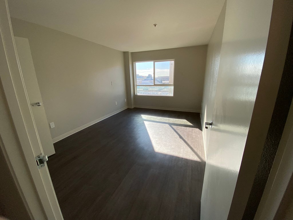 an empty living room with wood floors and a window