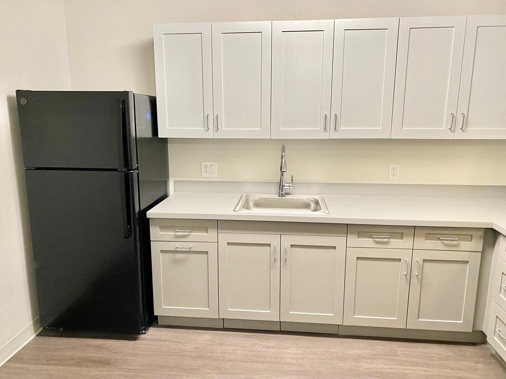 a kitchen with white cabinets and a black refrigerator