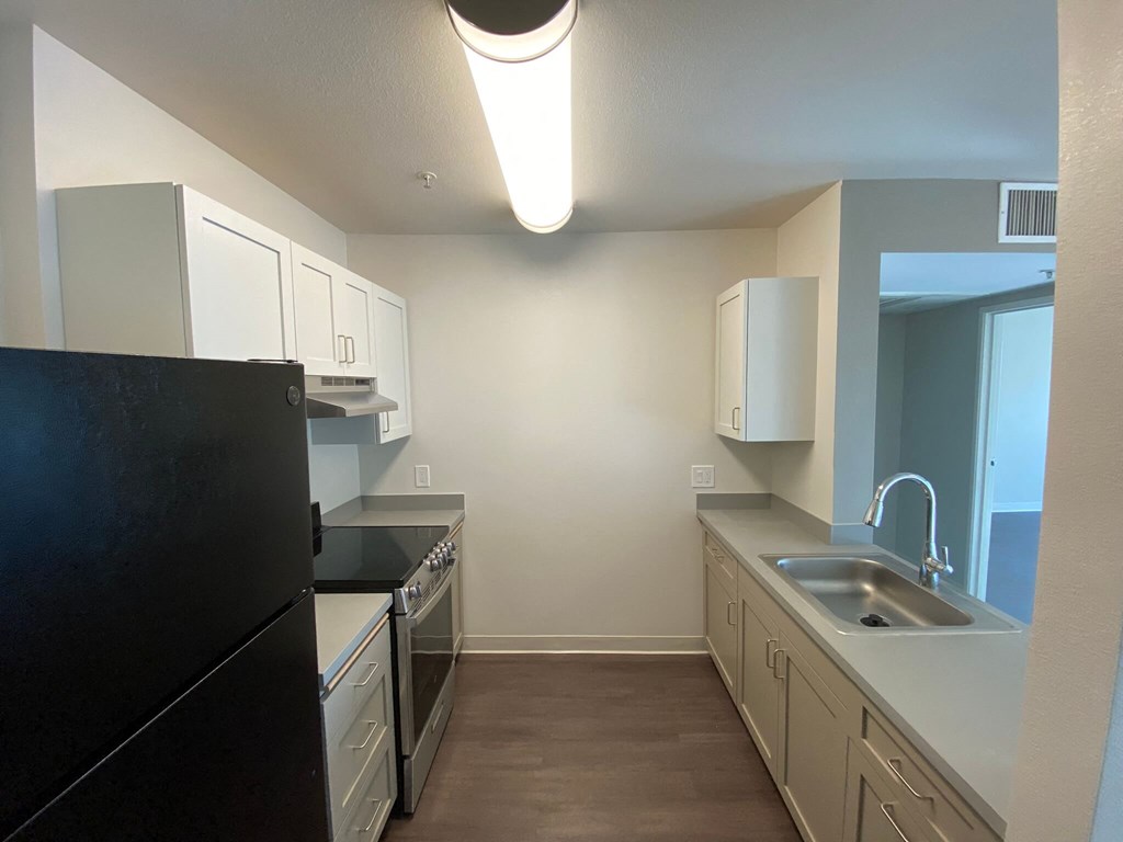 a kitchen with white cabinets and a black refrigerator