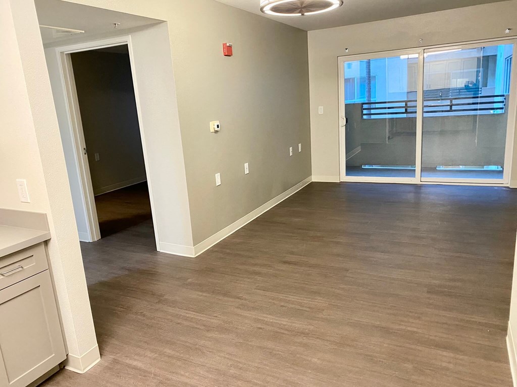 an empty living room with a hard wood floor and a glass door