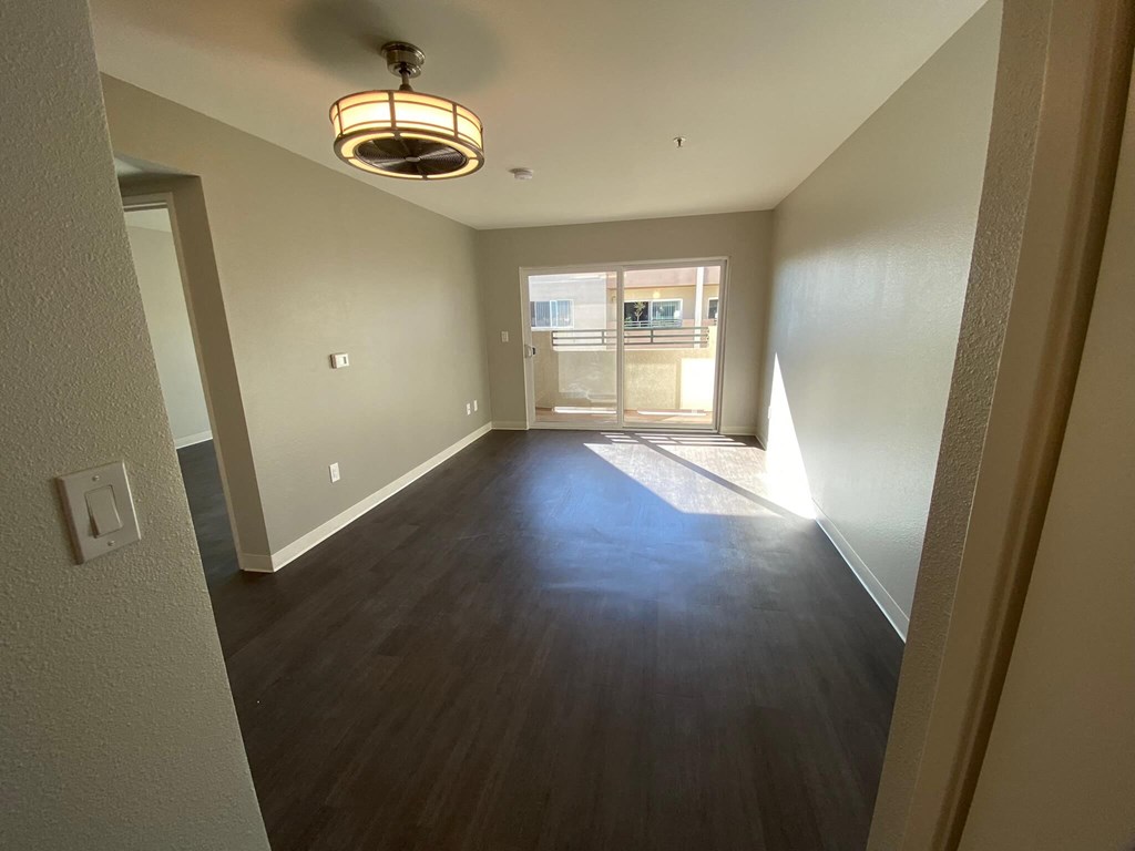 a empty living room with wood flooring and a window