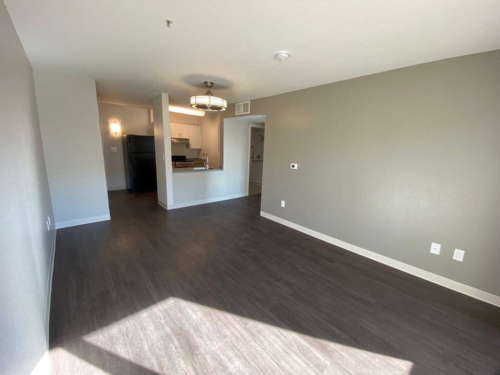 a empty living room with wood flooring and a ceiling fan