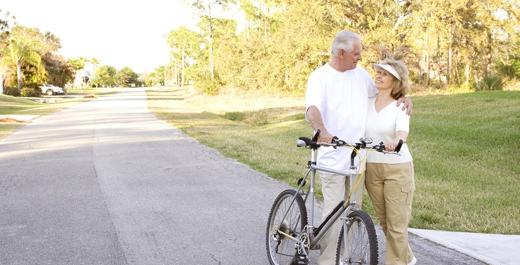 a man and a woman walking a bike down a sidewalk