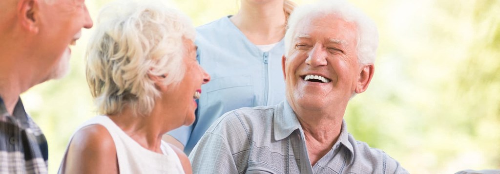 an older man and woman laughing with a group of people