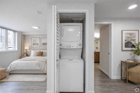 A white washing machine is built into a wall in a modern bedroom.