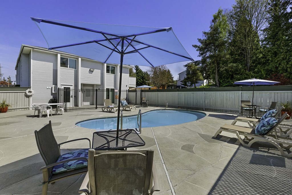 Cool Swimming Pool with Lounge Chairs and Shaded Bistro Table Set at Campo Basso Apartment Homes, Washington, 98087