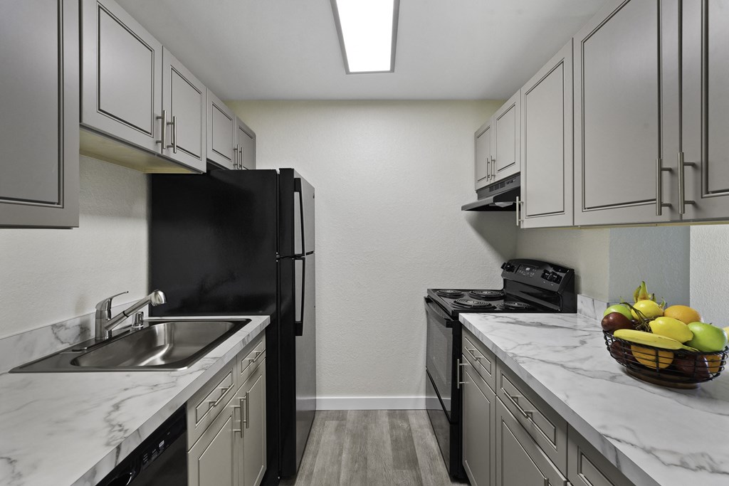 View into Kitchen with Updated Flooring, Grey Cabinets, and Marble-Look Countertops at Campo Basso Apartment Homes, Lynnwood