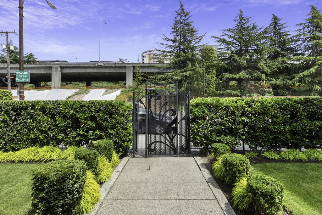 Gated Entrance in Carolina Court Apartment Homes with Greenery Growing on Gate, Manicured Lawn, and Shaped Shrubbery Lining the Walkway at Carolina Court, Seattle