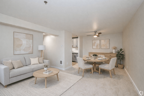 A living room with a couch, a coffee table, and a dining table with chairs.