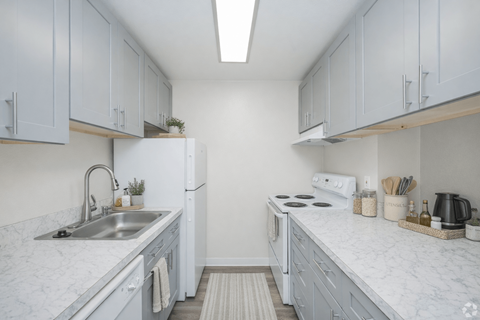 A kitchen with white cabinets and marble countertops.