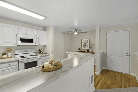 A kitchen with white cabinets and a marble countertop.