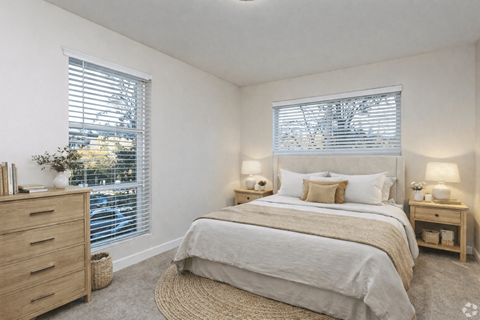 A bedroom with a large bed, a dresser, and two nightstands with lamps.