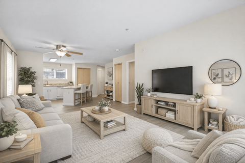 A living room with a grey couch, a wooden coffee table, and a flat screen TV mounted on the wall.