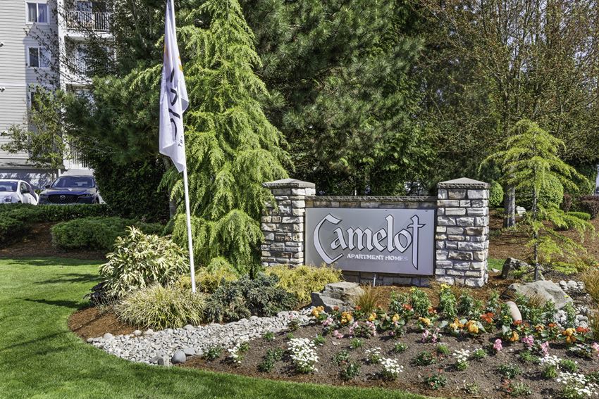 a sign in front of a building with a flag  at Camelot Apartment Homes, Everett, WA, 98204 - Photo Gallery 1