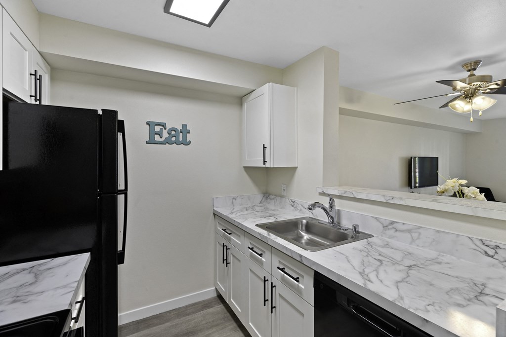 a kitchen with white cabinets and black appliances