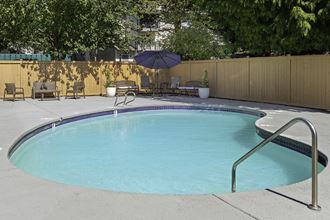 Fenced pool area with patio seating and an umbrella Fenced pool area with patio seating and an umbrella at Casa Blanca Apartment Homes, Everett, WA, 98204 - Photo Gallery