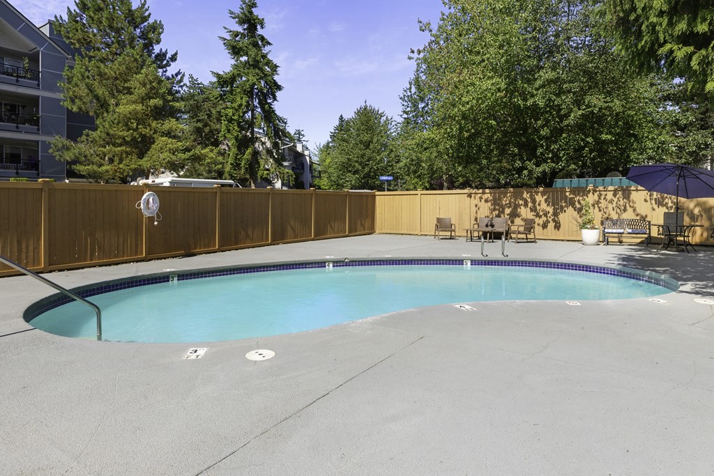 a pool with a fence around it and trees in the background at Casa Blanca Apartment Homes, Everett, 98204