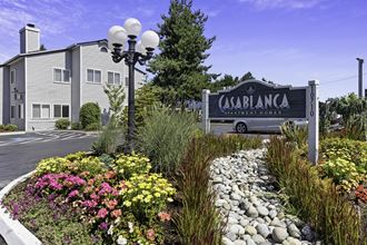 Casablanca Property Sign with flowers, bushes, and stone path in front at Casa Blanca Apartment Homes, Washington