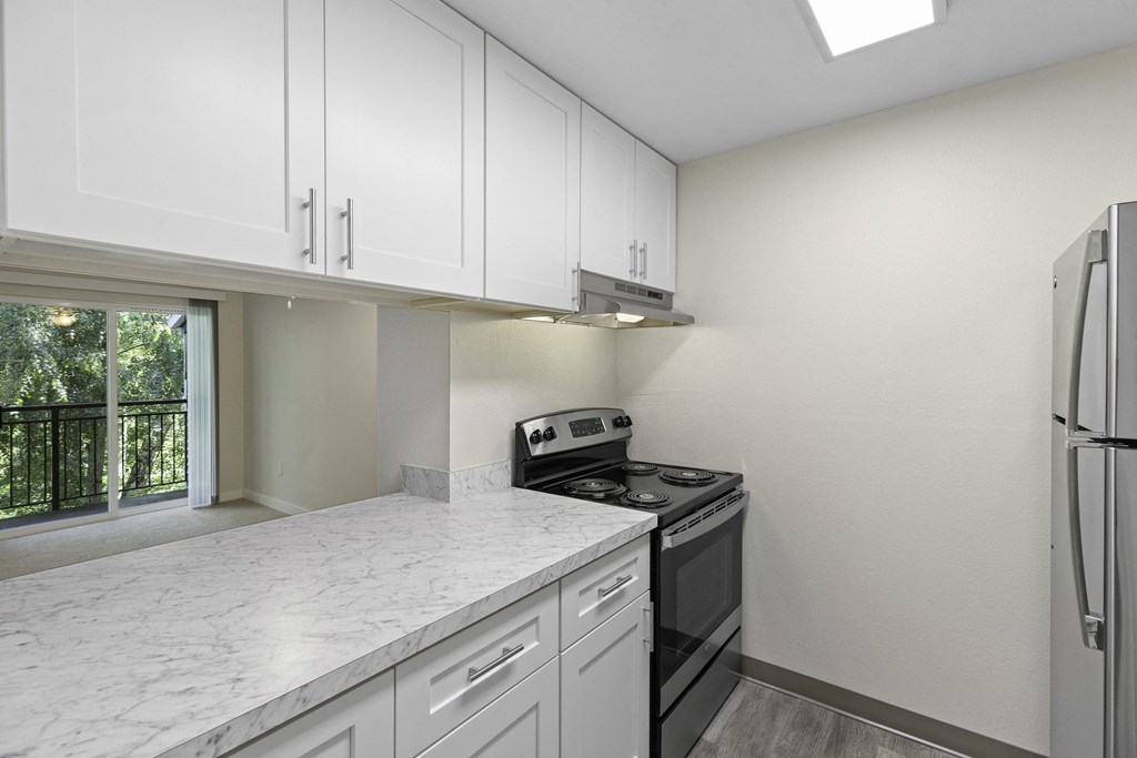 kitchen with efficient appliances, plank flooring, and white cabinetry at Casa Blanca Apartment Homes, Everett, WA