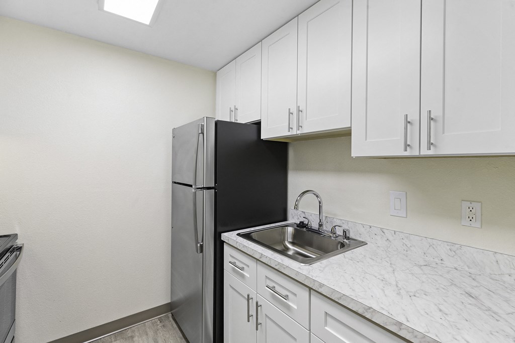 a kitchen with white cabinets and a stainless steel refrigerator at Casa Blanca Apartment Homes, Everett, WA