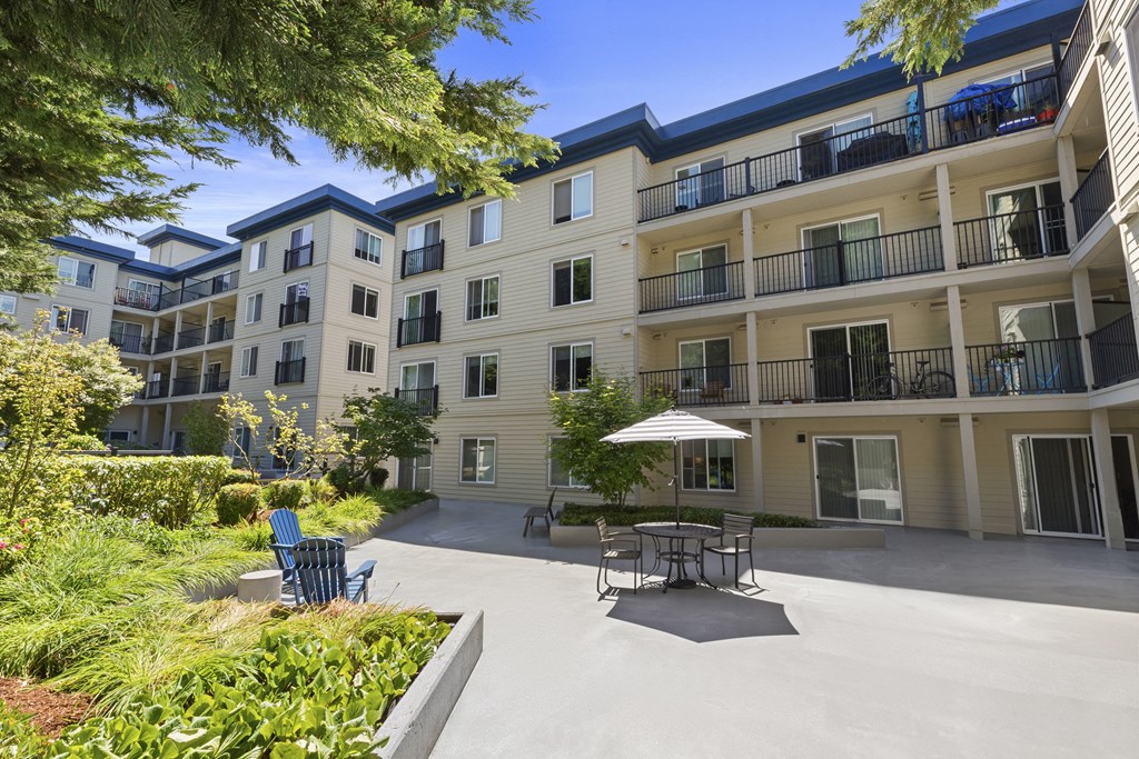 a patio with a table and chairs in front of the property building at Guinevere Apartment Homes, WA 98103