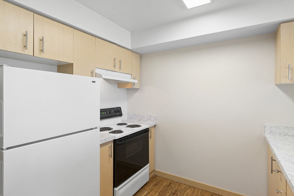 a kitchen with plank wood-style floors and white appliances at Guinevere Apartment Homes, Washington