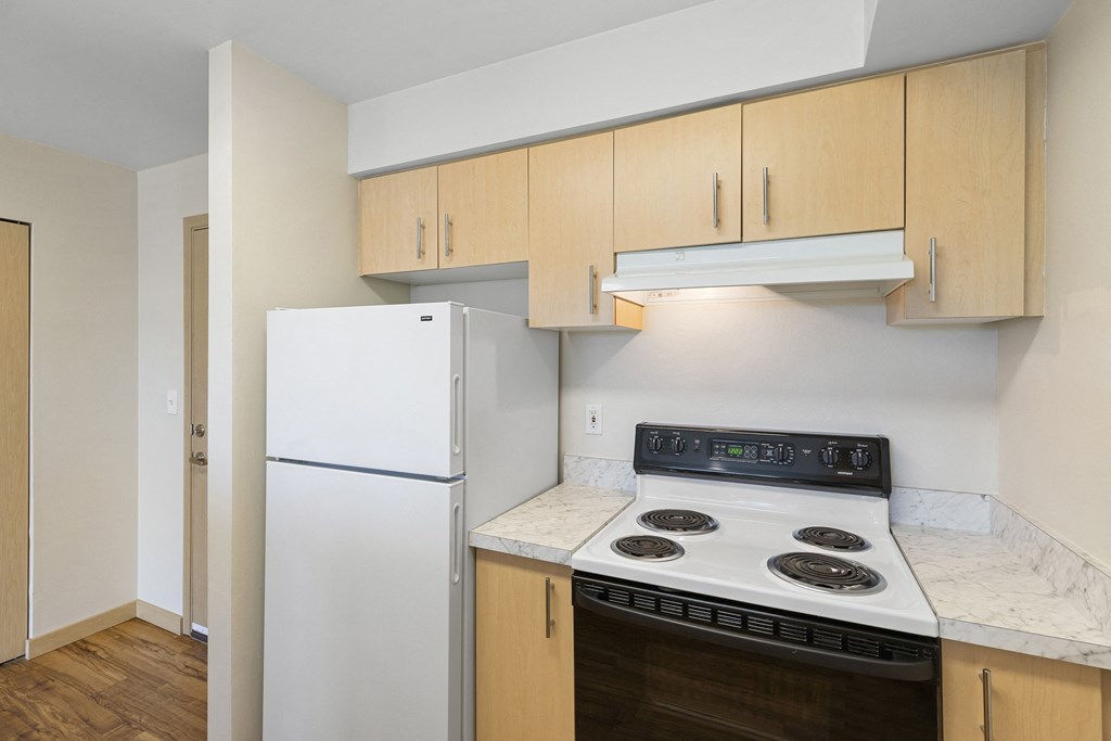 a kitchen with white appliances and wooden cabinets at Guinevere Apartment Homes, Seattle