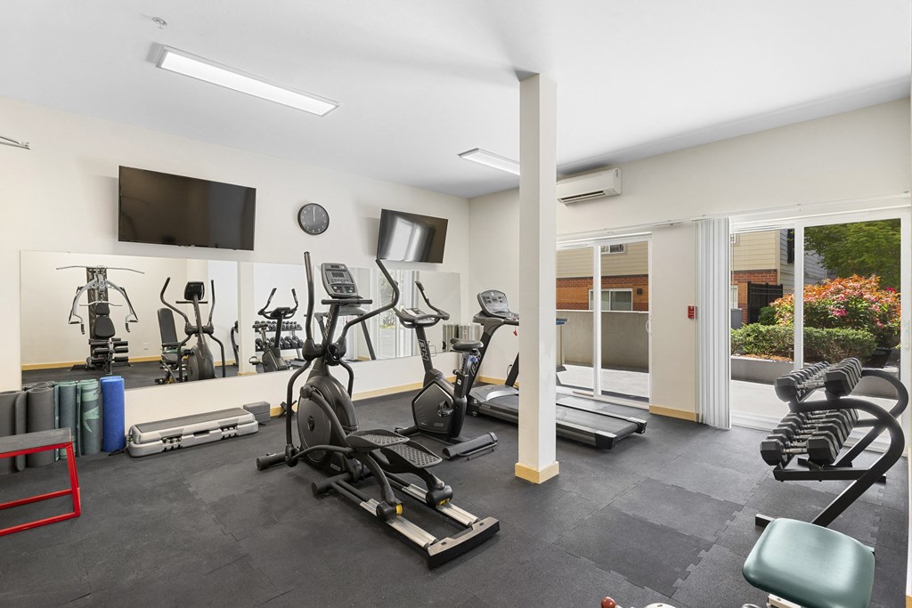 a gym with cardio equipment and a flat screen tv at Guinevere Apartment Homes, Washington