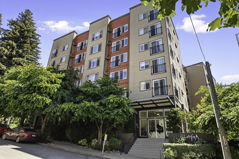 Front view of property building with an awning and trees for shade at Illumina Apartment Homes, Seattle, WA