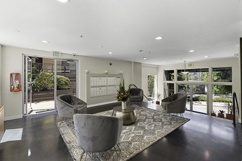 A spacious living room with grey chairs and a patterned rug.