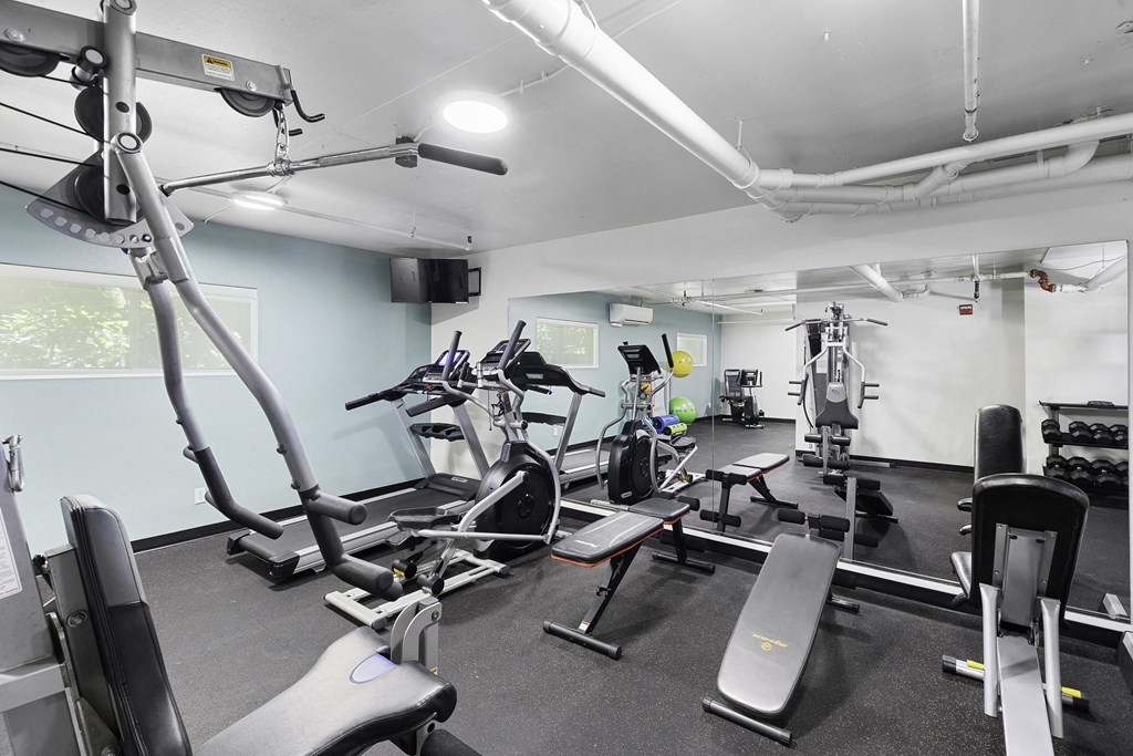 a room filled with lots of different types of exercise equipment for resident use at King Arthurs Court, Seattle, 98125