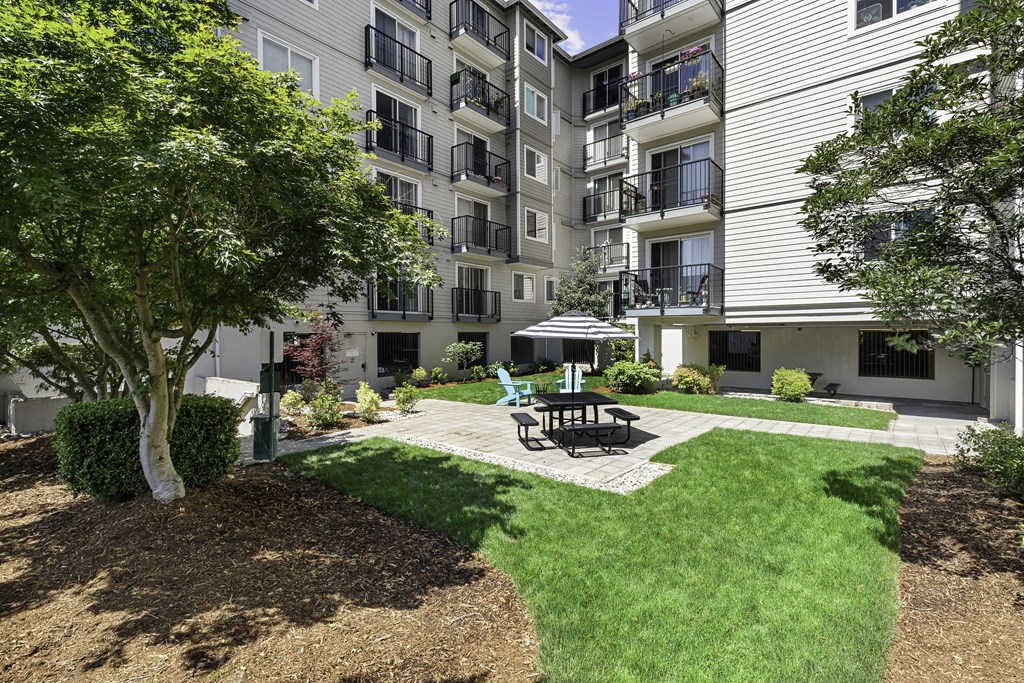Resident Outdoor Lounge Space with a patio and picnic table with umbrella at King Arthurs Court, Seattle, Washington