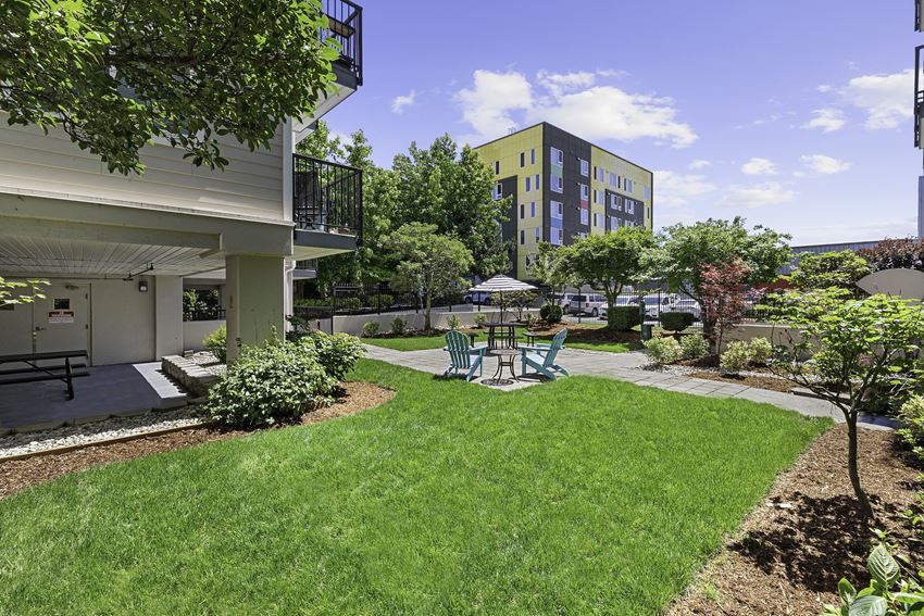 Green grassy area with a patio table and chairs Green grassy area with a patio table and chairs at King Arthurs Court, Seattle, Washington - Photo Gallery