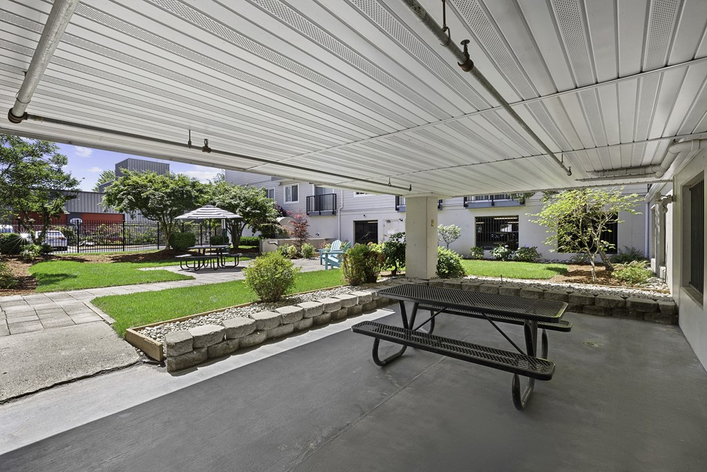 a covered patio with a picnic table and courtyard area in the background at King Arthurs Court, Seattle, 98125