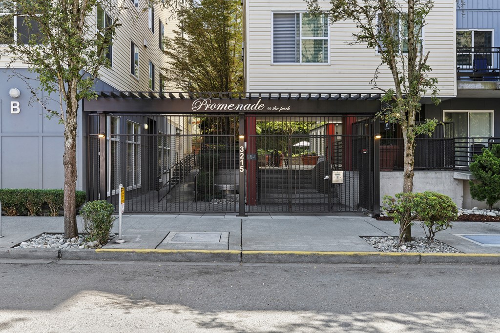 the entrance to property building with a black gate and property signage in white lettering on the front of it at Promenade at the Park Apartment Homes, Seattle, Washington 98125