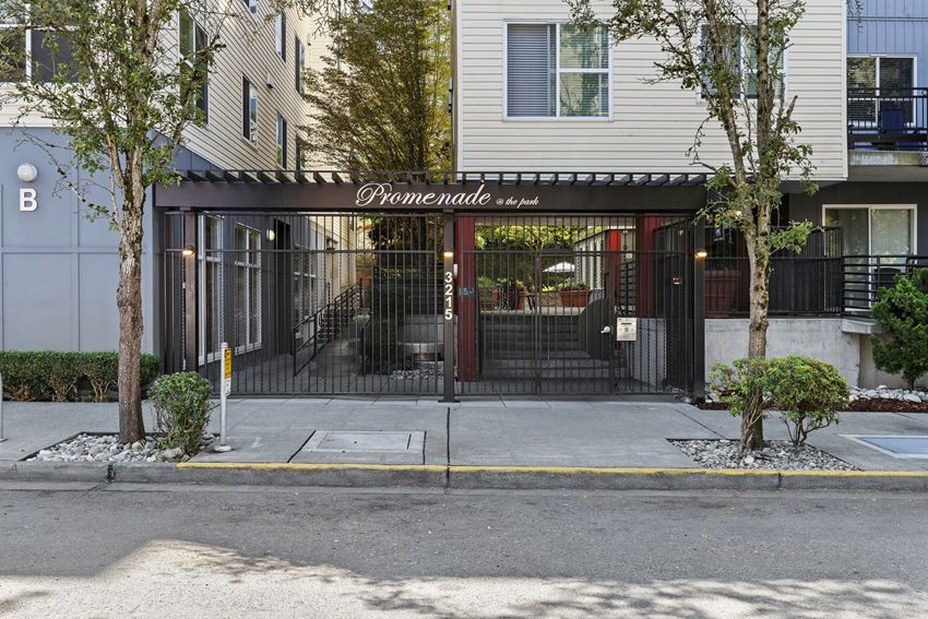 the entrance to property building with a black gate and property signage in white lettering on the front of it the entrance to property building with a black gate and property signage in white lettering on the front of it at Promenade at the Park Apartment Homes, Seattle, Washington 98125 - Photo Gallery