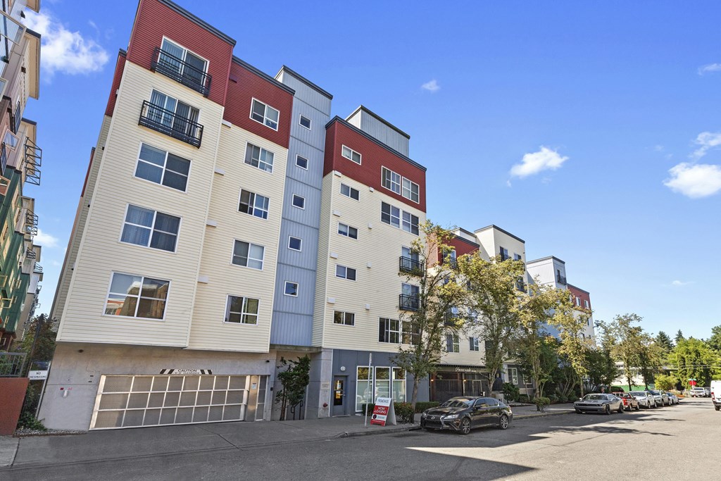 an apartment building with a parking lot in the foreground and a blue sky in the background at Promenade at the Park Apartment Homes, Seattle, 98125