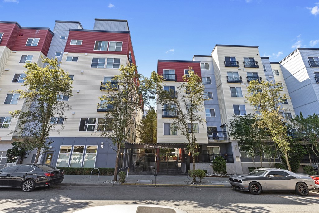 Property building on a city street with cars parked in front of it at Promenade at the Park Apartment Homes, WA 98125