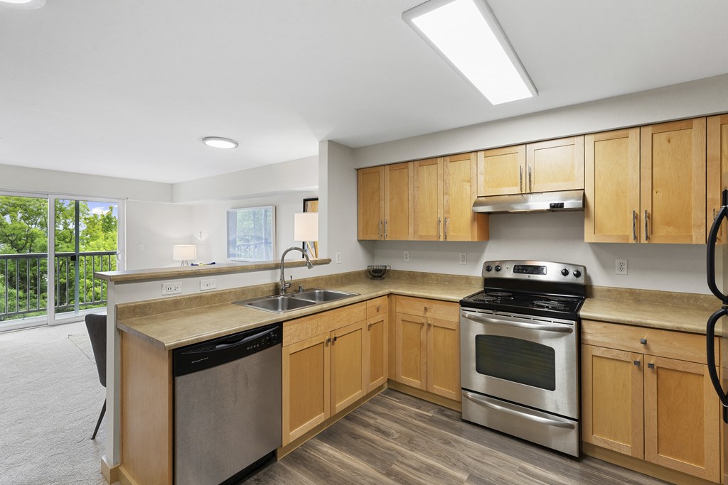 a kitchen with wooden cabinets and stainless steel appliances a kitchen with wooden cabinets and stainless steel appliances at Villaggio Apartment Homes, Tacoma, 98402