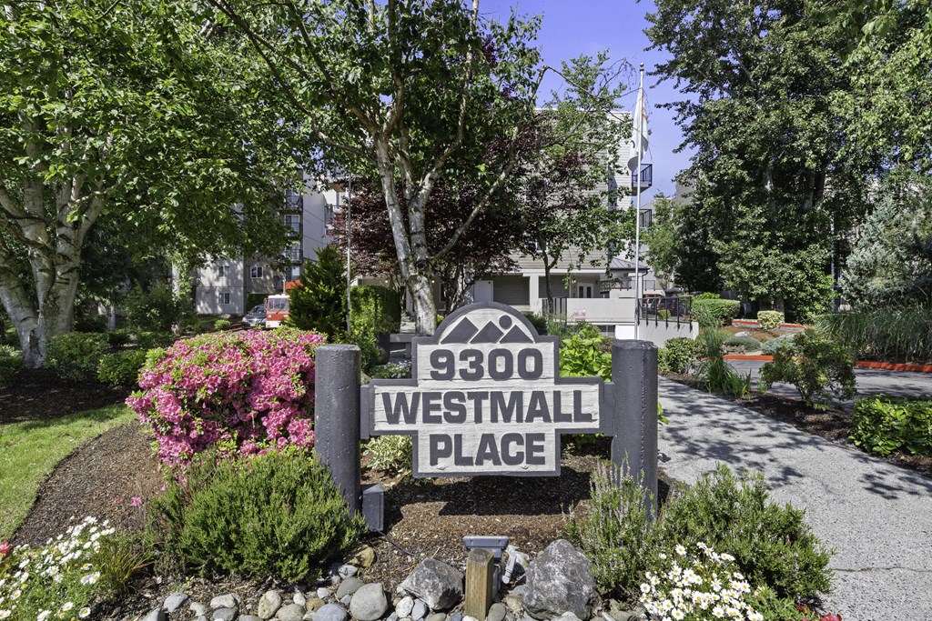 Property Sign with Address surrounded by flowers and trees in the background at West Mall Place Apartment Homes, Everett, Washington